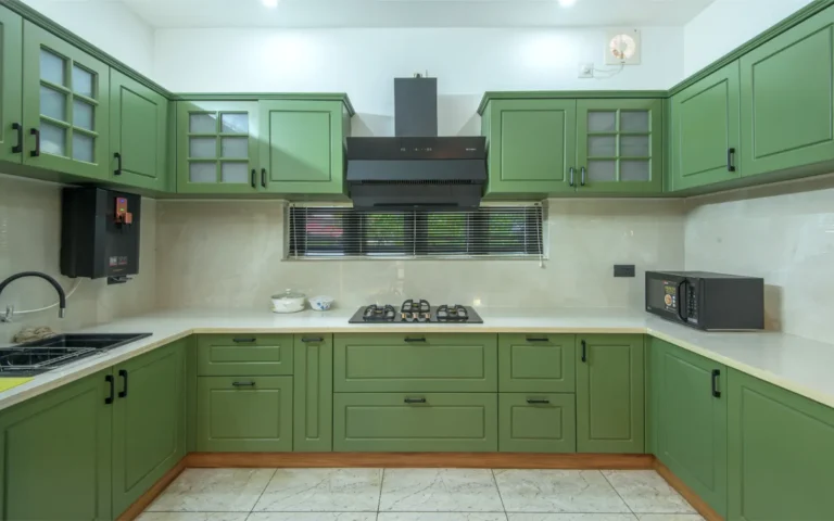 Modular kitchen with green cabinets and black chimney – Castle Residence Thiroor