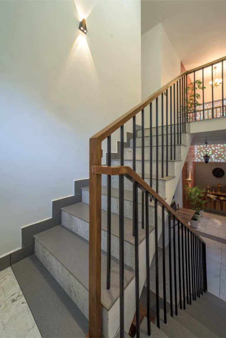 Marble staircase with wooden railing and warm lighting – Castle Residence Thiroor