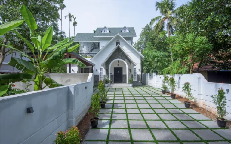 White colonial-style front elevation with green roof – Castle Residence Thiroor