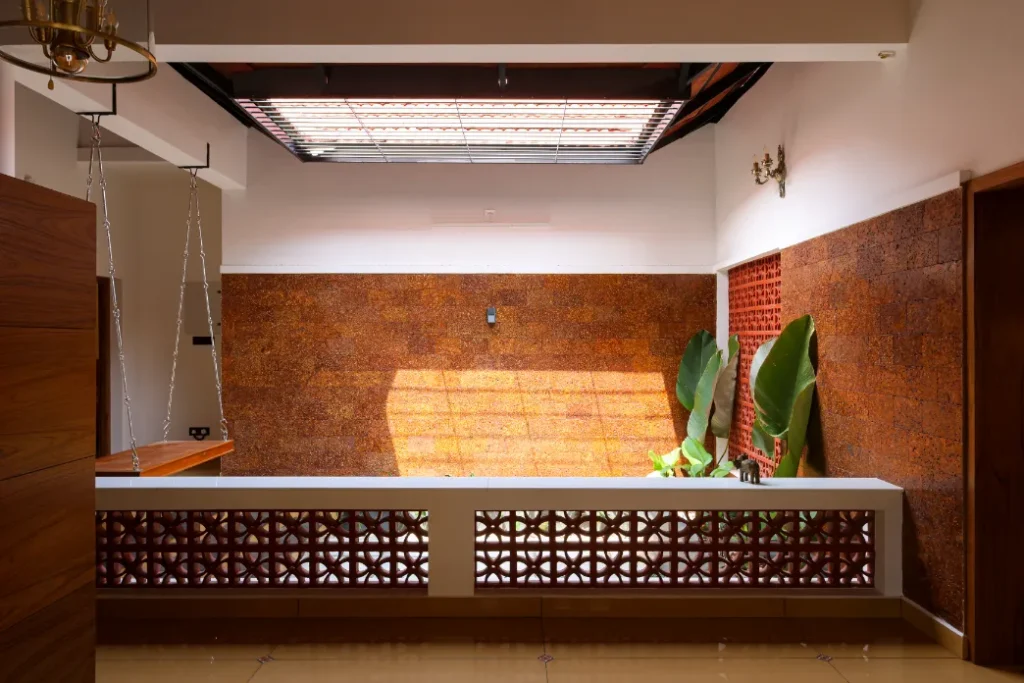 Sunlit courtyard with laterite walls and indoor plants – Courtyard House Wadakkanchery