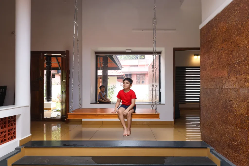 Child sitting on wooden swing in courtyard – Courtyard House Wadakkanchery by VB Infra