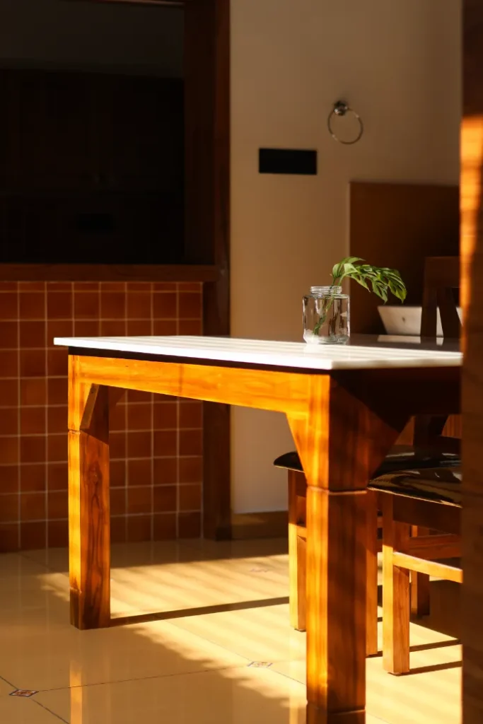 Wooden dining table with sunlight reflection – Courtyard House Wadakkanchery