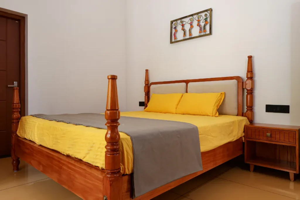 Guest bedroom with yellow bedding and wooden furniture – Courtyard House Wadakkanchery