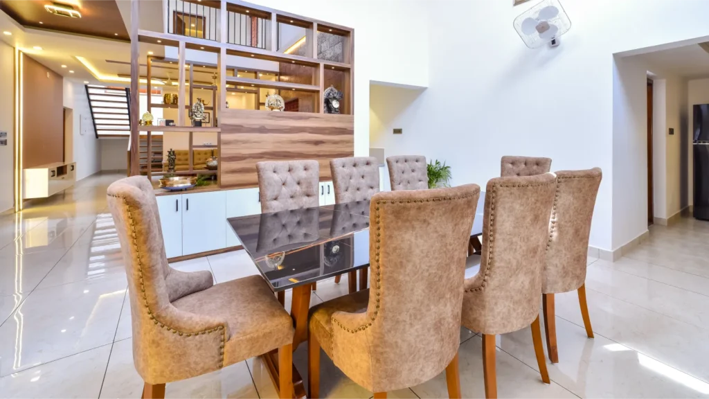 Dining area with eight-seater upholstered chairs – Trikkur Residence Thrissur