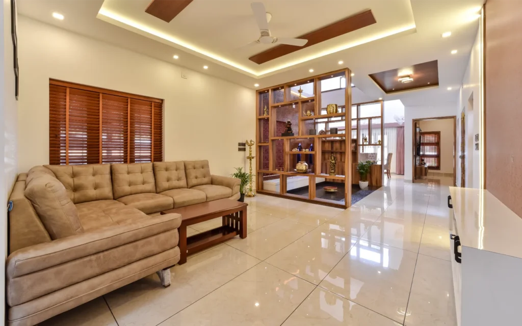 Living area with L-shaped sofa and partition display shelves – Trikkur Residence Thrissur