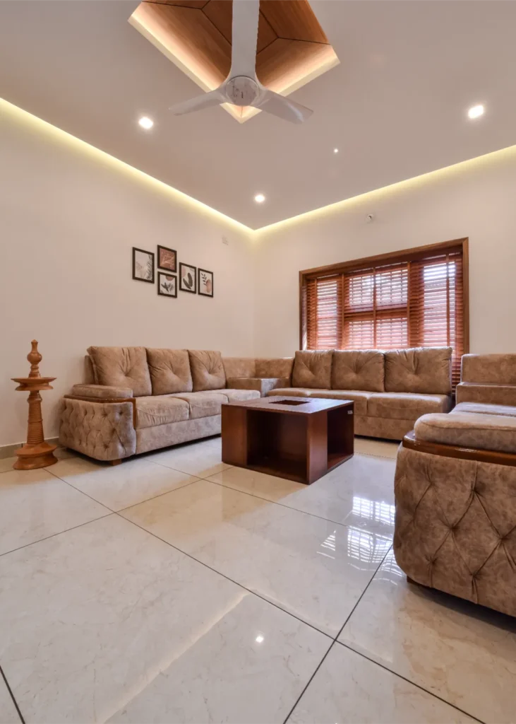 Living room with L-shaped beige sofa and modern ceiling lighting – Trikkur Residence Thrissur