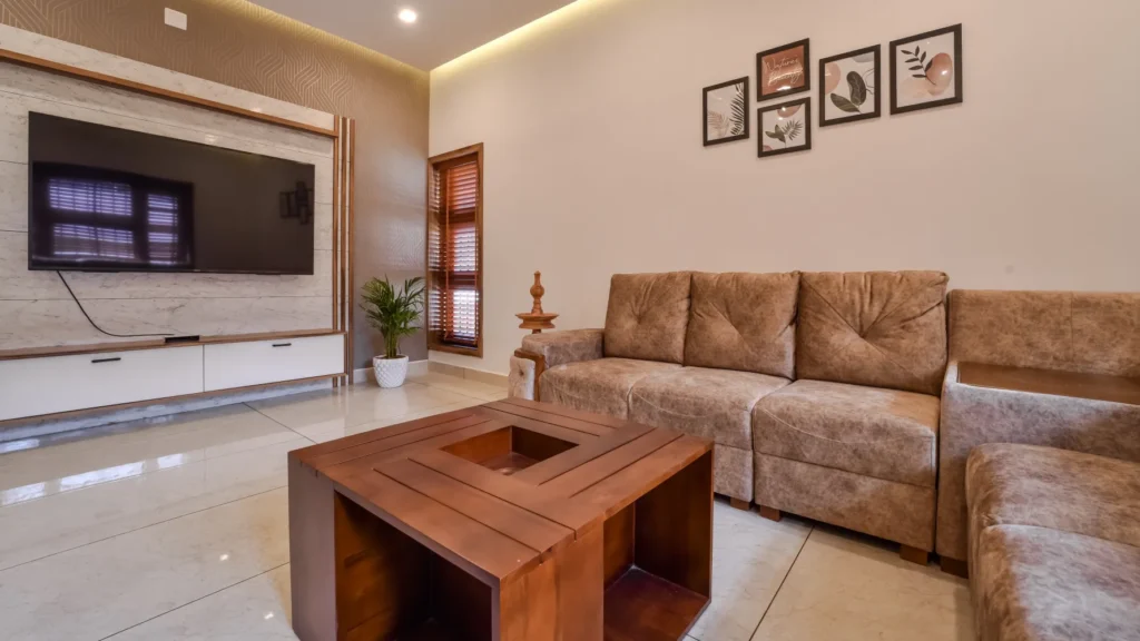 TV wall unit with beige sofa set and indoor plant – Trikkur Residence Thrissur