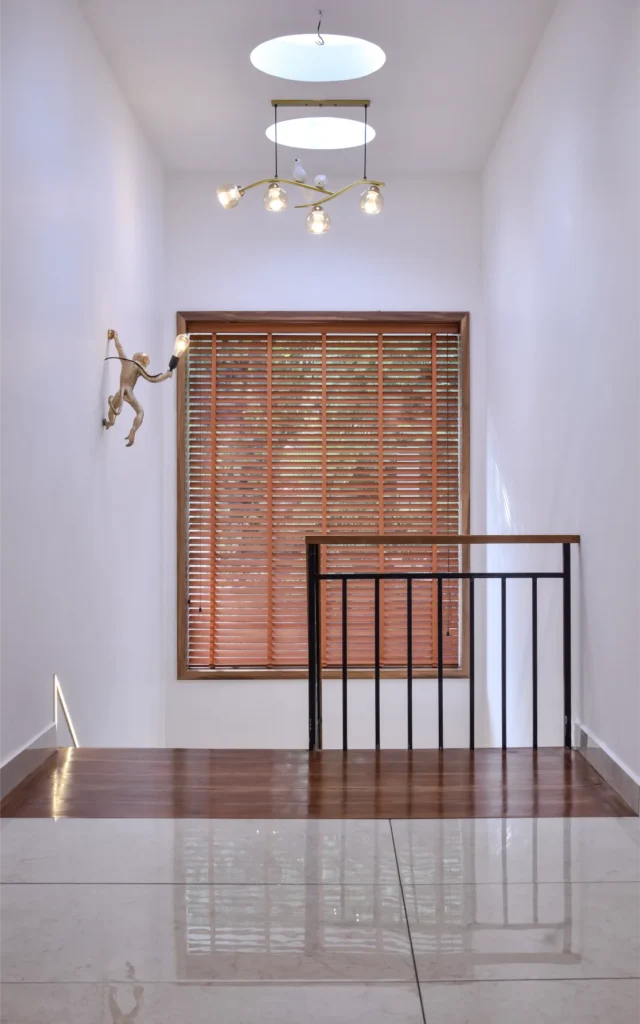 Stair landing with skylight and hanging light fixture – Trikkur Residence Thrissur