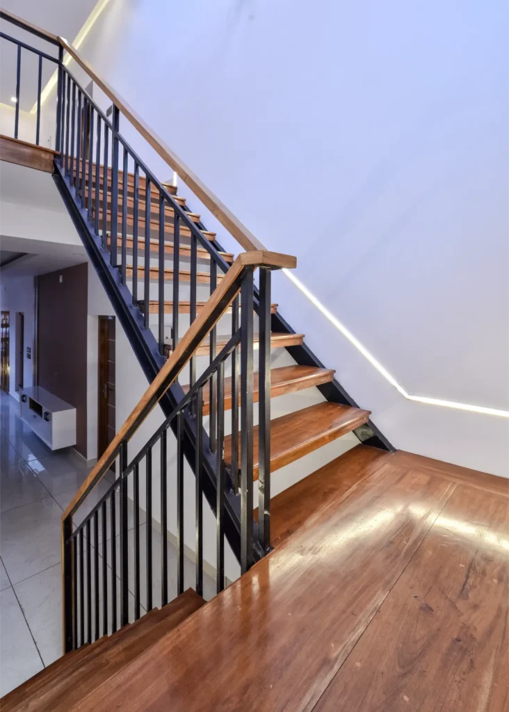 Wooden staircase with metal railing and LED strip lights – Trikkur Residence Thrissur