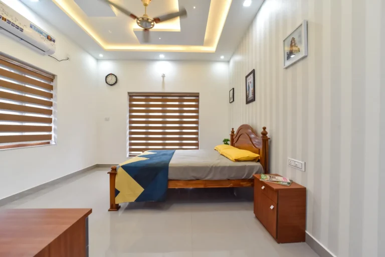 Minimal bedroom with wooden furniture and striped blinds – Varghese Residence Wadakkanchery