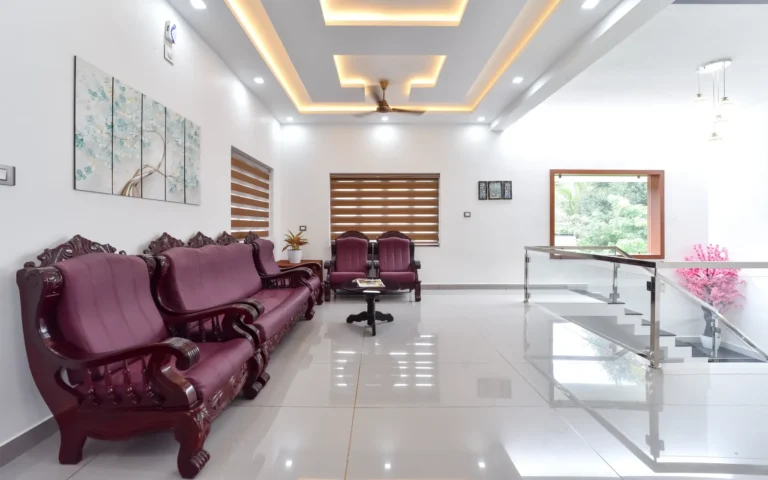 First floor living area with maroon sofa and false ceiling lighting – Varghese Residence Wadakkanchery