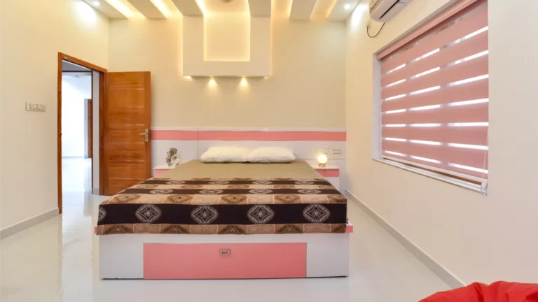 Minimal bedroom interior with pink blinds and warm lighting – Varghese Residence Wadakkanchery