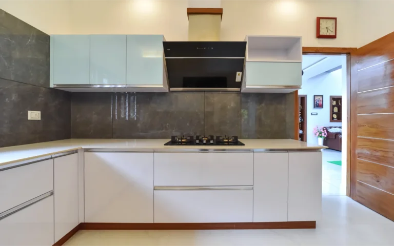 Kitchen cooktop wall with glossy cabinets and chimney – Varghese Residence Wadakkanchery