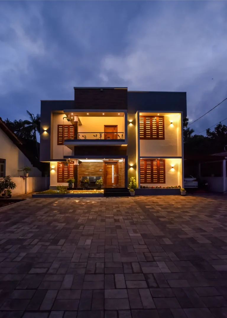 Contemporary home exterior at dusk with warm lighting – Varghese Residence Wadakkanchery