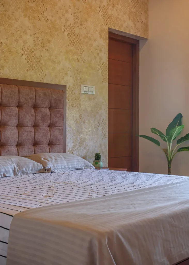 Guest bedroom with beige padded headboard and wallpaper – Vasudevam Residence Chalakudy