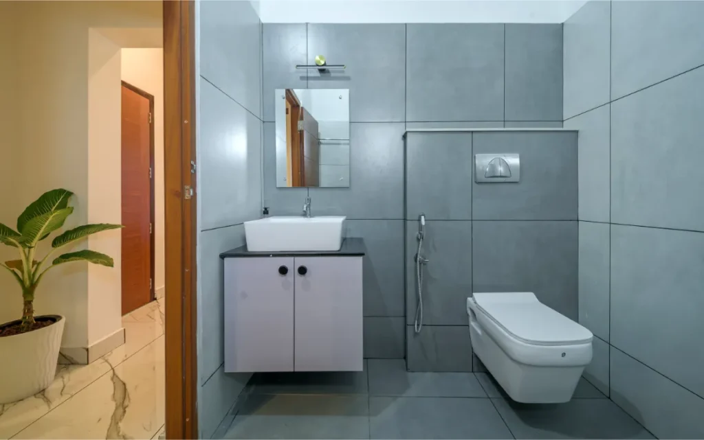 Modern grey bathroom with wall-mounted toilet and vanity – Vasudevam Residence Chalakudy