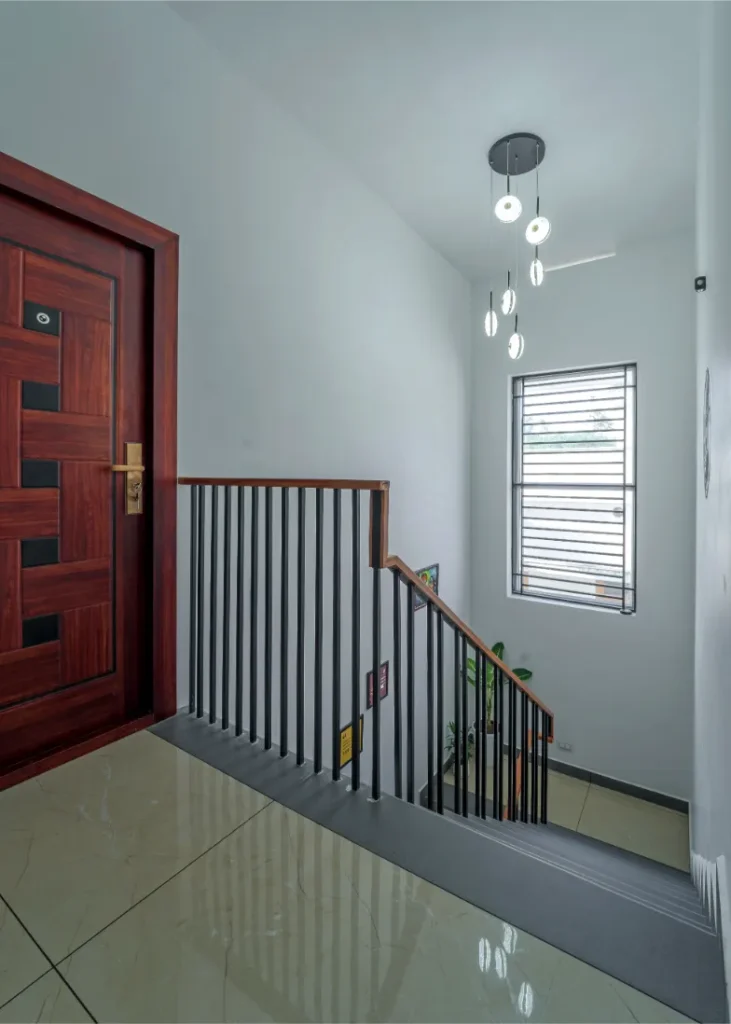 Staircase landing with modern hanging lights and window – Vasudevam Residence Chalakudy