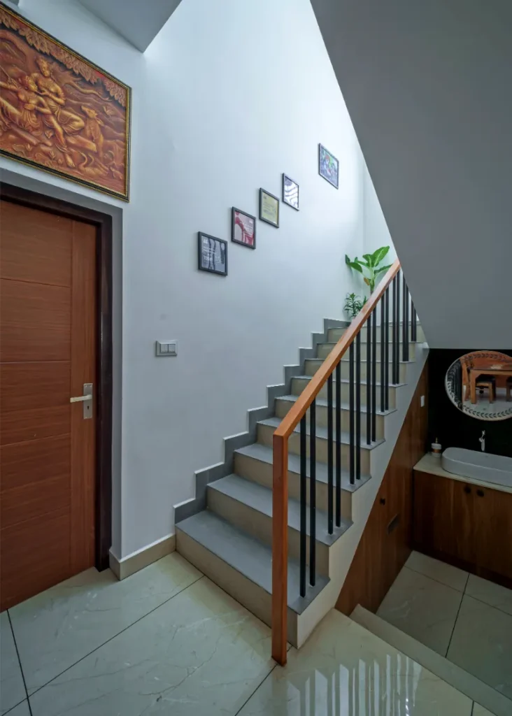 Staircase with wooden handrail and wall art – Vasudevam Residence Chalakudy