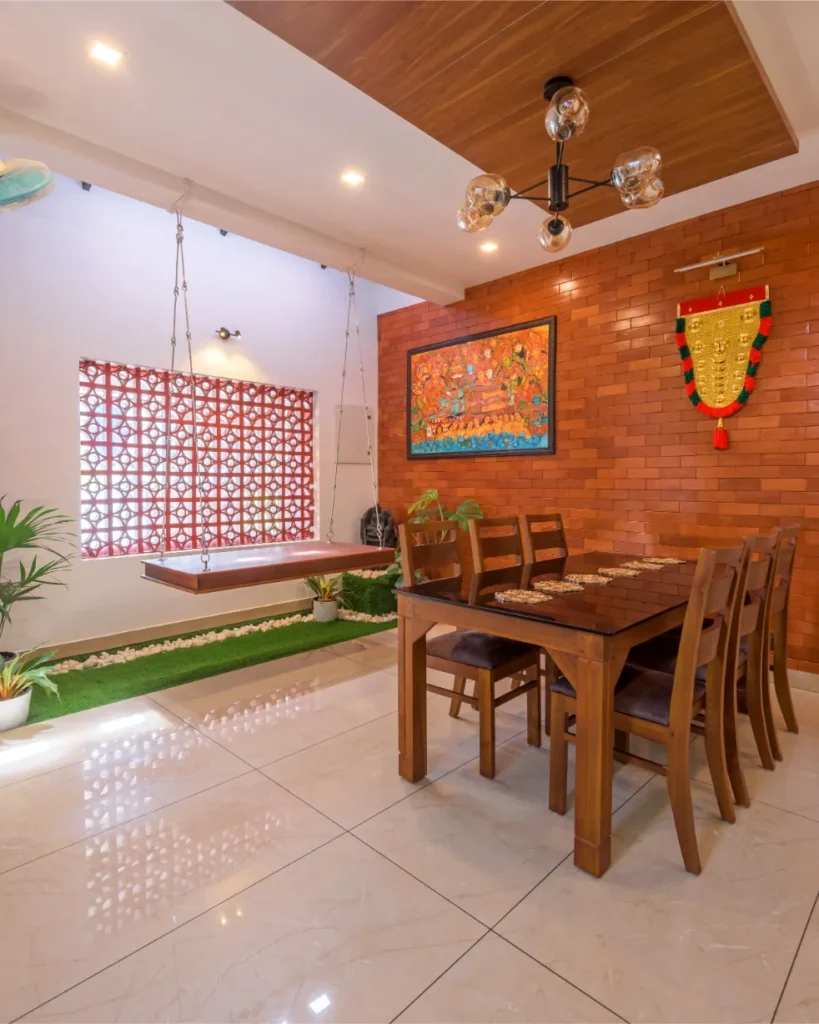 Wooden swing and dining table under pendant lights – Vasudevam Residence Chalakudy