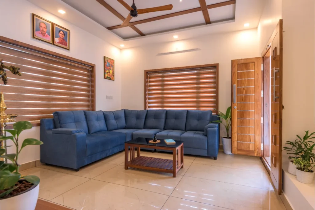 Living room with blue sofa and wooden door – Vasudevam Residence Chalakudy
