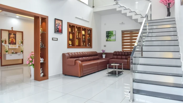 Double height living area with brown leather sofa and trophy shelf – Varghese Residence Wadakkanchery