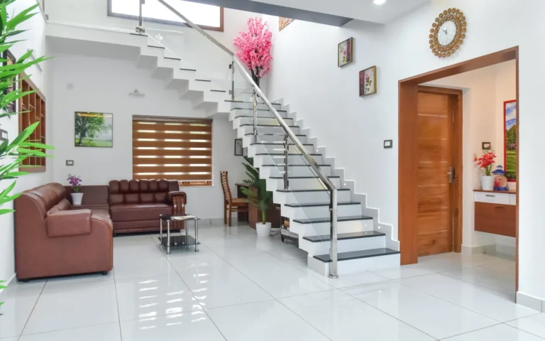 Staircase with glass railing and modern seating area – Varghese Residence Wadakkanchery
